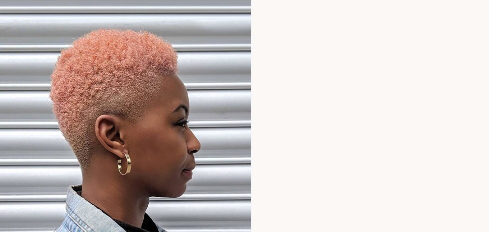 Woman with short, coily hair, dyed a peach colour.